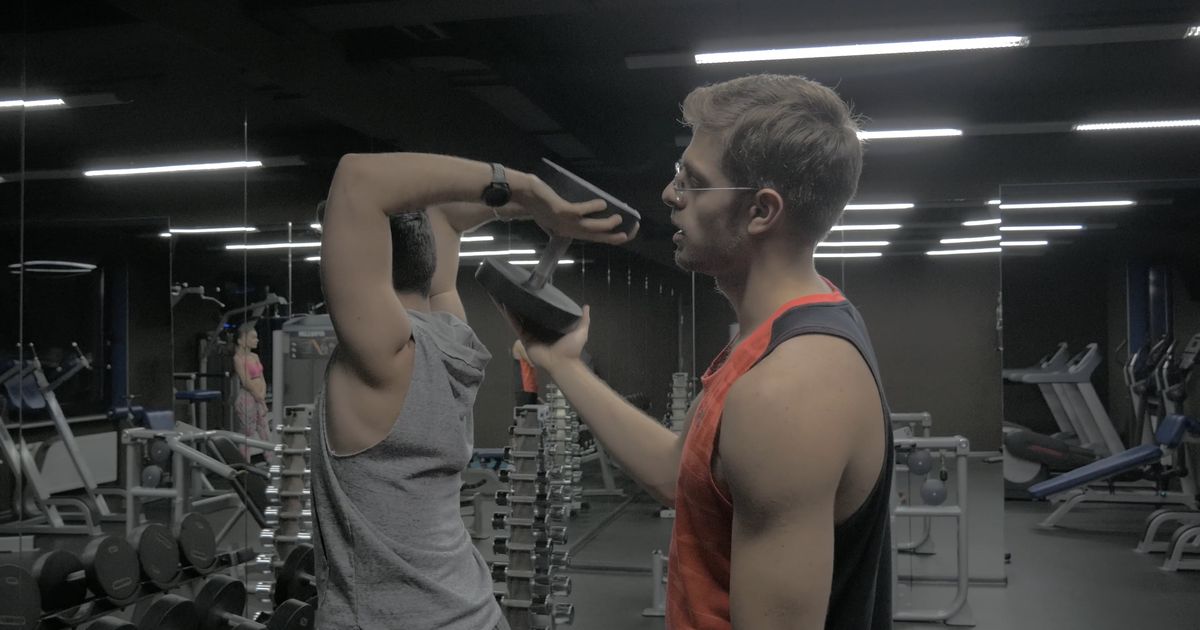 A trainer spotting a client mid-exercise