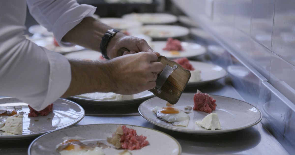 A chef plating dishes at the kitchen pass