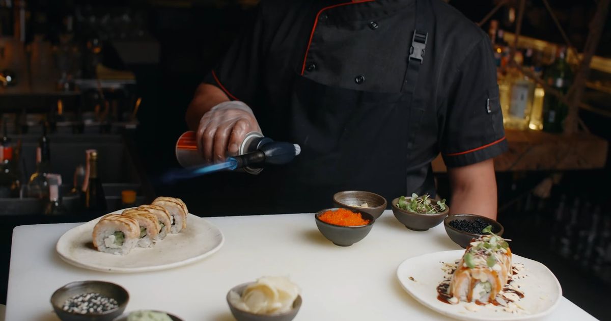 A chef finishing a dish with a blowtorch