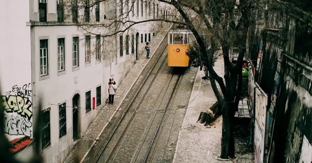 A yellow Lisbon tram climbing a narrow cobbled street
